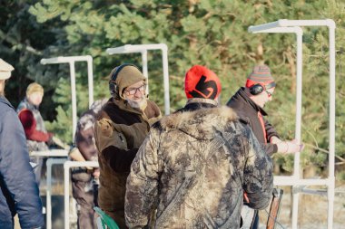 Tuzak ya da hedef atışı, kamuflajlı sporcu kil güvercine pompalı tüfekle ateş ediyor, yarışmalarda ormanın ve gökyüzünün arka planı. Rusya, Ryazan '11 Aralık 2021