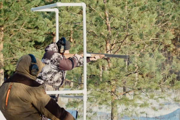 トラップやスケート撮影 迷彩服のスポーツマンは 競技会の森と空の背景にある粘土鳩で散弾銃から撮影します ロシア リャザン 12月2021 — ストック写真