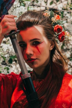 Geleneksel kimano giymiş genç bir kız çiçek açan bahçesinde Japon samuray kılıcı katana ile savaşçı kadın suretinde.