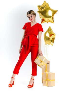 Kırmızı kostümlü güzel sarışın kadın beyaz stüdyo arka planında hediye kutuları tutuyor. Kadınlar Günü 'nü, Sevgililer Günü' nü, doğum gününü, yıldönümünü kutluyoruz. Tatil konsepti alışverişi