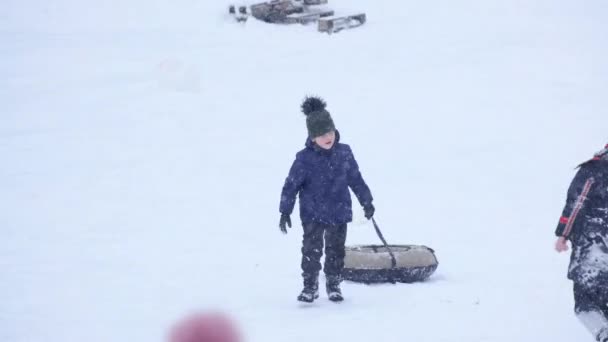 暗闇の中の小さなかわいい少年は 冬の氷のスライド 冬の子供のゲーム 冬の公園の子供をスライドさせます 少年はチューブでスライドを登る — ストック動画