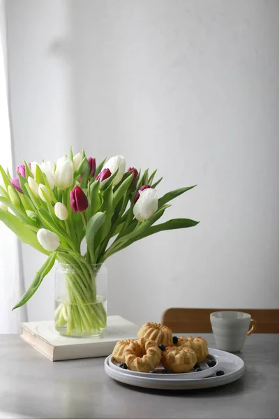 Mini gâteaux bundt aux fruits sur assiette, tasse de café et bouquet de tulipes. — Photo