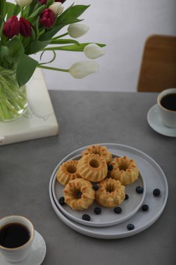 Meyveli mini kekler, masada iki fincan kahve. Kahvaltı.