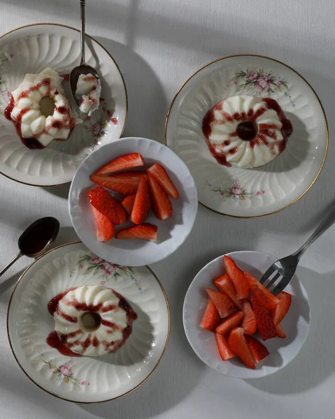 Panna cotta dolce italiana con marmellata di frutta e pezzi freschi di fragole su piatti. Vista dall'alto — Foto Stock