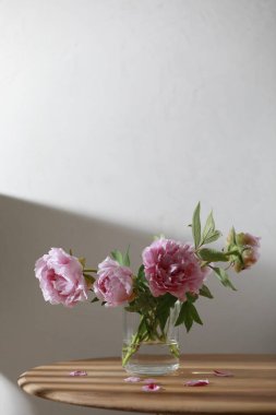 Pastel pembe şakayık çiçekleri ahşap masadaki cam vazoda.. 