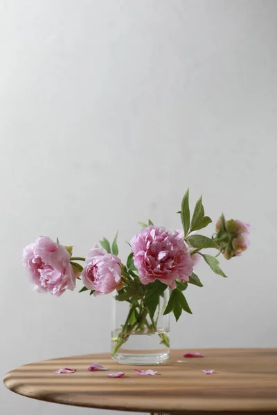 Pastel pink peony flowers bouquet in a glass vase on wooden table. — Photo