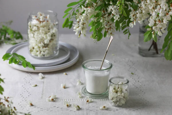 Akazienblüten und Zucker in einem Glas auf grauem Hintergrund. — Stockfoto