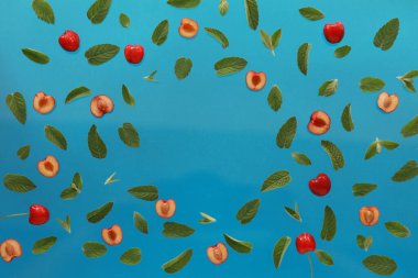 Yaz arkaplanı, taze kiraz meyveli çerçeve ve mavi arka planda nane. Düz yatıyordu. Yaz meyveleri konsepti. Boşluğu kopyala