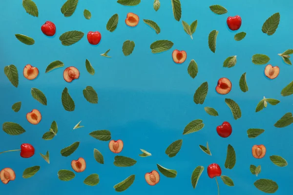 Yaz arkaplanı, taze kiraz meyveli çerçeve ve mavi arka planda nane. Düz yatıyordu. Yaz meyveleri konsepti. Boşluğu kopyala
