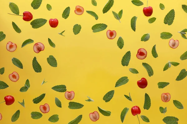 Yaz arkaplanı, taze kiraz meyveli çerçeve ve sarı arka planda nane. Düz yatıyordu. Yaz meyveleri konsepti. Boşluğu kopyala
