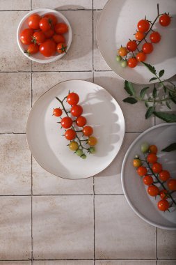 Fresh red cherry tomatoes on branch on white plates. 