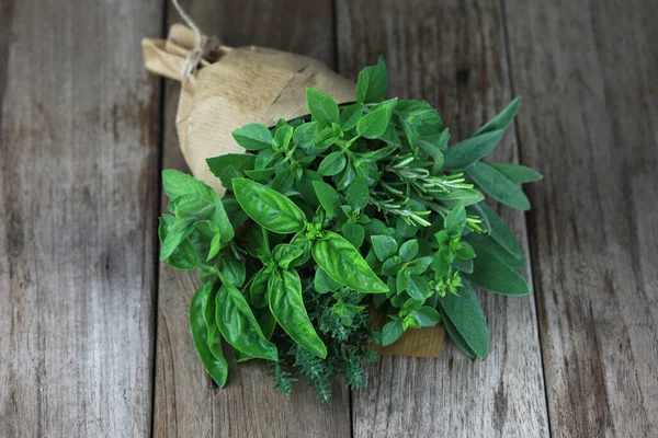 Fresh herb bouquet with rosemary, thyme, mint, sage and different kind of basil. Farm-to market herbs and sprigs tied with string in a bouquet. Shot on wooden textures.