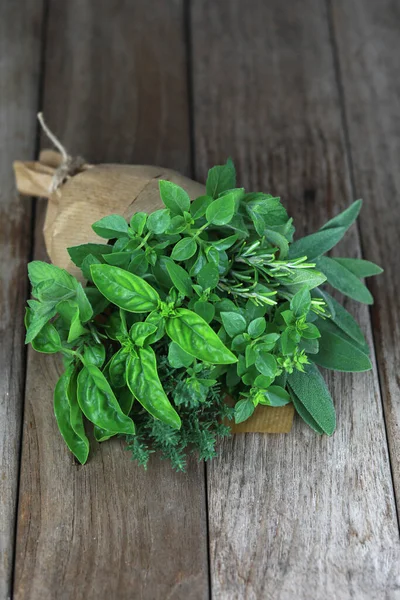 Biberiyeli taze bitki buketi, kekik, nane, adaçayı ve farklı türde fesleğen. Bir bukete iple bağlanmış sebzeler ve filizler. Ahşap dokularda çekiliyor..