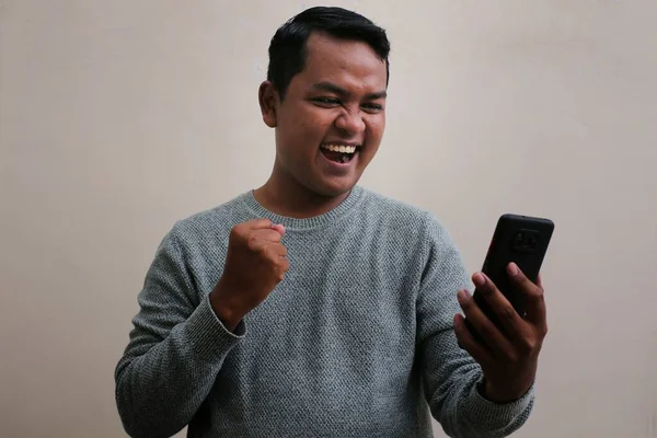 Asian Man Wearing Sweater Looking His Smartphone While Laughing Looking —  Fotos de Stock