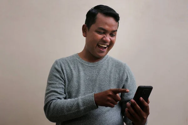 Asian Man Wearing Sweater Looking His Smartphone While Laughing Looking —  Fotos de Stock