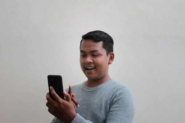 Asian Man Wearing Sweater Looking His Smartphone While Laughing Smiling — стоковое фото