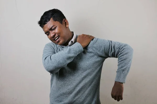 Seorang Pria Asia Yang Mengenakan Sweater Memegang Bahu Kirinya Yang — Stok Foto