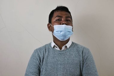 a young asian man wears a mask the wrong way because his nose is not covered and is at risk of contracting disease