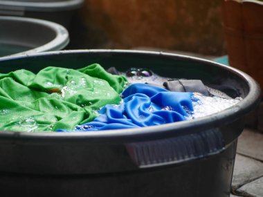 colorful clothes soaked with soap, soaking laundry in the tub, manual washing concept