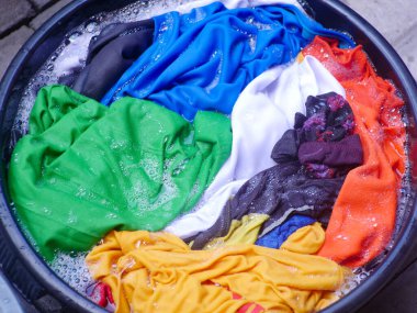 colorful clothes soaked with soap, soaking laundry in the tub, manual washing concept