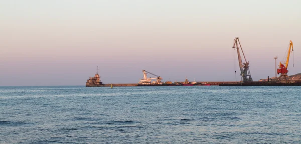 La grúa flotante y el rompeolas protector y las grúas portuarias, Teodosia, la Crimea, Ucrania, la tarde Fotos De Stock