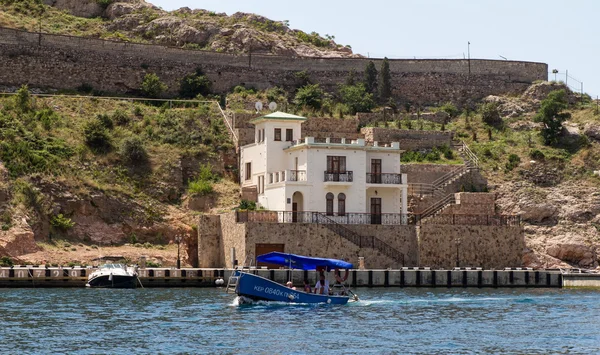 Un petit bateau à moteur avec des touristes sur le fond des bâtiments modernes et des murs de la forteresse génoise du XIVe siècle, Balaklava, Crimée, Ukraine — Photo