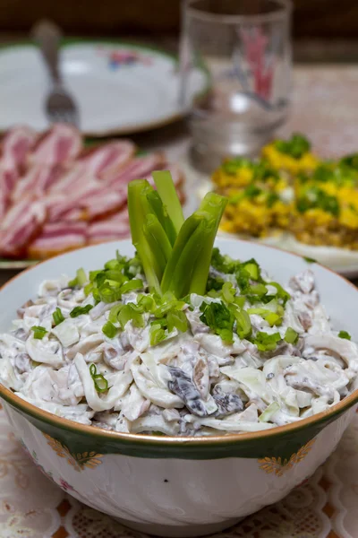 Ensalada de calamares con champiñones, adornada con cebollas verdes picadas en la mesa festiva Fotos de stock libres de derechos