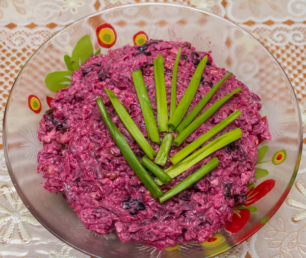 Салат из свеклы, чеснока, чернослива и грецких орехов украшен зеленым луком — стоковое фото