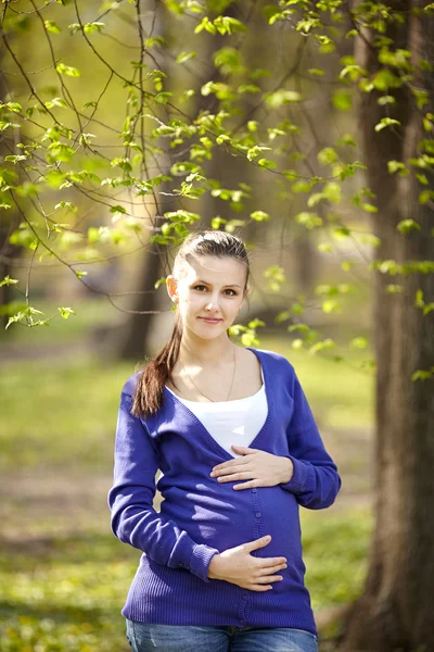 Mulher grávida posando em um parque verde — Fotografia de Stock
