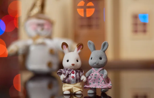 Замечательная пара игрушечных зайцев против красивого дома и снеговика — стоковое фото