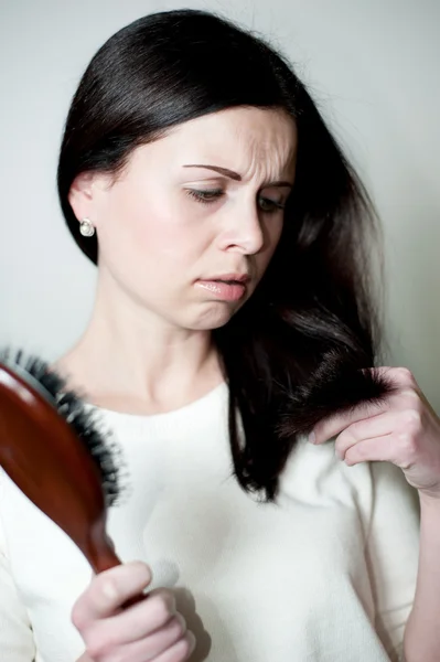 Girl looks at tips of the hair — Stock Fotó