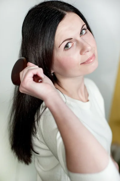 Beautiful girl combs hair — Stock Photo, Image