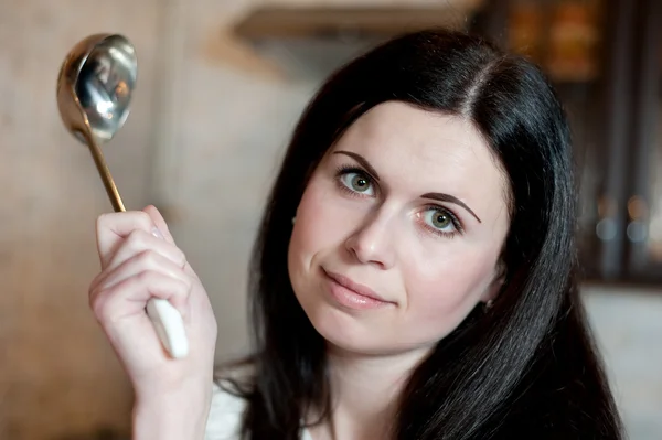 Jonge brunette met een portie lepel in keuken — Stockfoto