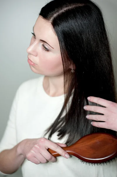 Jovem mulher fazendo seu belo cabelo escuro — Fotografia de Stock