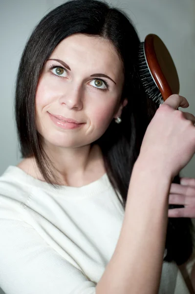 Beautiful girl combs hair — Stock Photo, Image