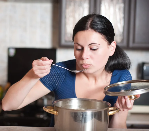 Jeune femme au foyer cuisine la nourriture dans la cuisine — Photo