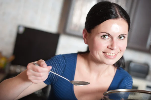 Ung hemmafru kockar mat i köket — Stockfoto