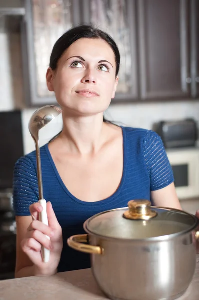 Jovem dona de casa cozinha comida na cozinha — Fotografia de Stock