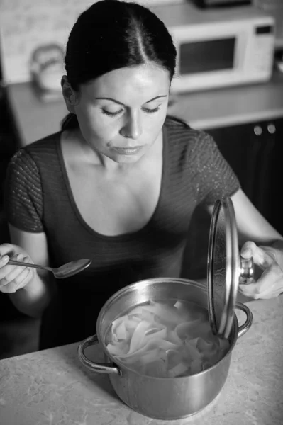 Young housewife cooks food in kitchen — Stock Photo, Image