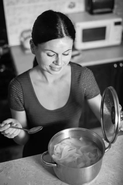 Jonge huisvrouw kookt voedsel in keuken — Stockfoto