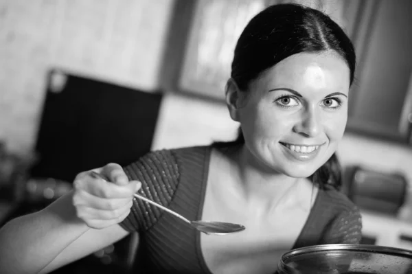 Jonge huisvrouw kookt voedsel in keuken — Stockfoto