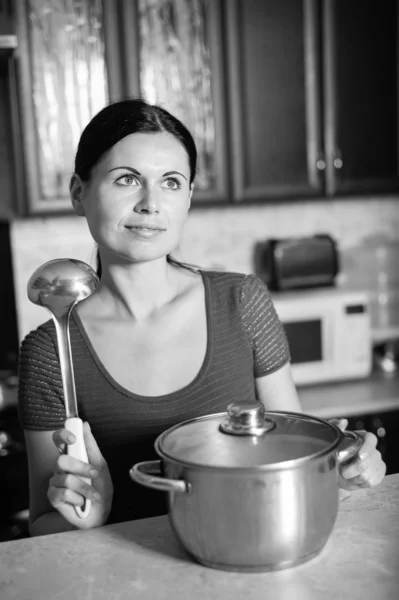 Young housewife cooks food in kitchen — Stock Photo, Image