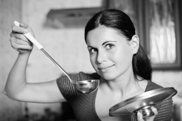 Jonge huisvrouw kookt voedsel in keuken — Stockfoto