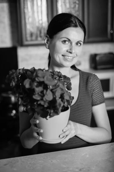 Νεαρή γυναίκα κρατά λουλούδι σε μια κατσαρόλα — Φωτογραφία Αρχείου