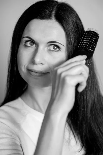 The smiling brunette combs hair — Stock Photo, Image