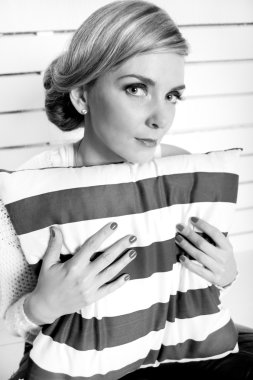 genç kız bir yere oturur ve bir yastık kucaklıyor