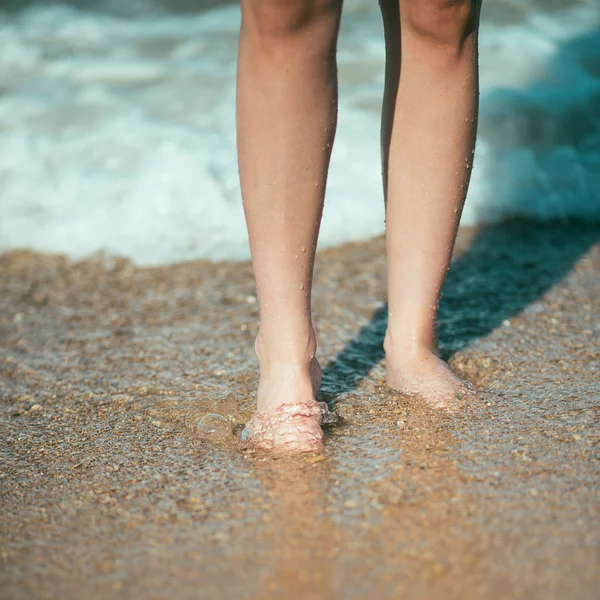 Perna feminina andando na praia no oceano — Fotografia de Stock