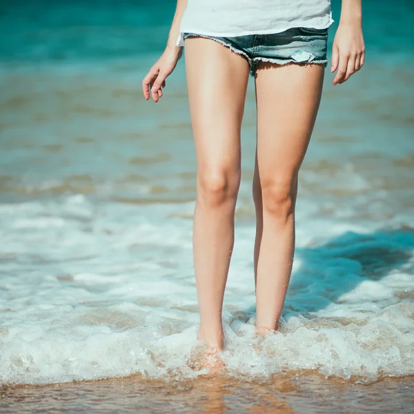 Kvinnliga ben promenerar på stranden i havet Stockfoto
