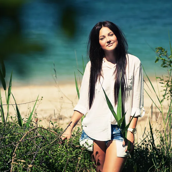 Menina bonita em tendas de jeans e uma camisa branca posa — Fotografia de Stock