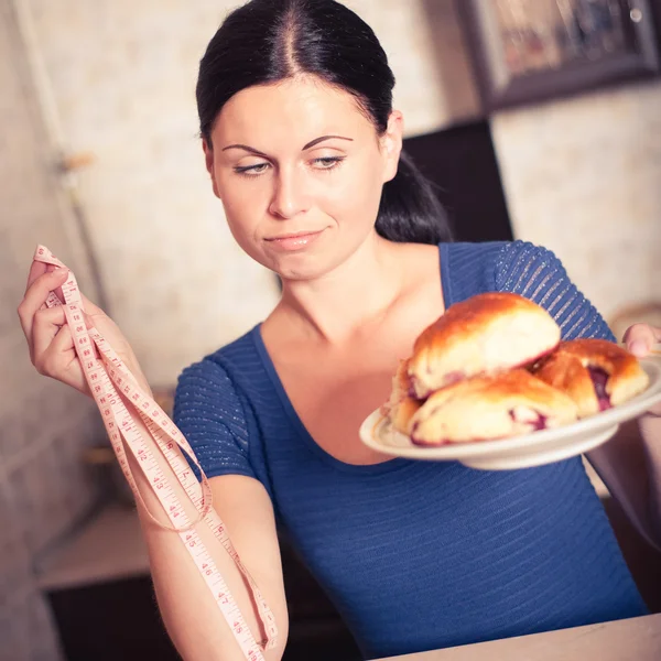 Jovem mulher segura torta e uma fita métrica — Fotografia de Stock